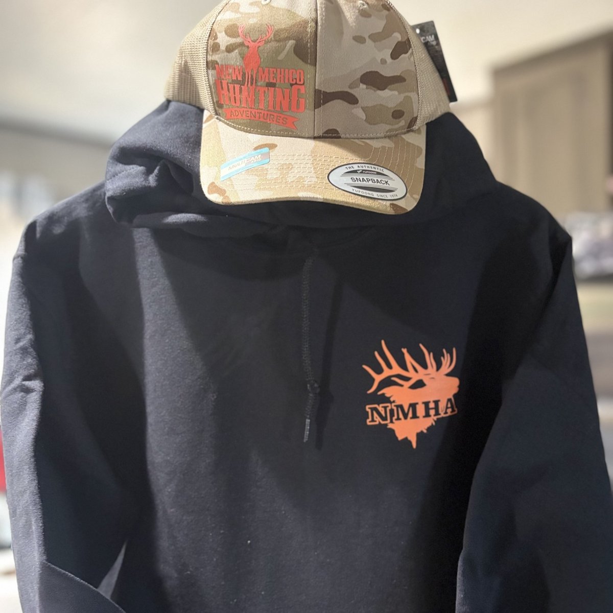 Camo New Mexico Hunting Adventures snapback hat on a black NMHA hoodie made by KB Custom Creations