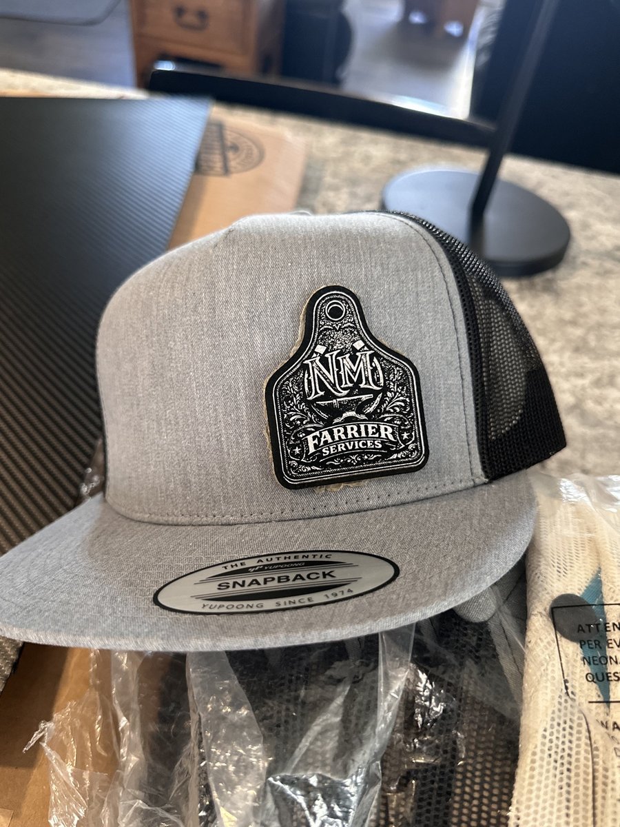 Gray snapback hat with a leather ear-tag patch for NM Farrier Services, by KB Custom Creations