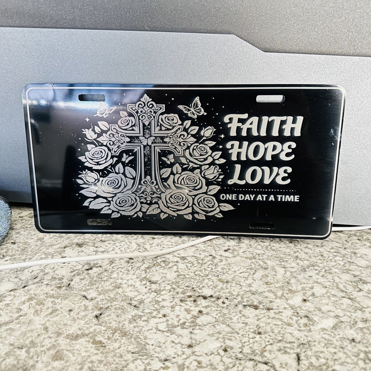 Black engraved license plate with a cross, roses, and a faith design, by KB Custom Creations