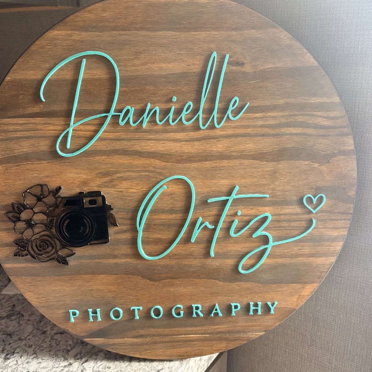 Round wooden business sign with raised teal script lettering for a photography business, made by KB Custom Creations