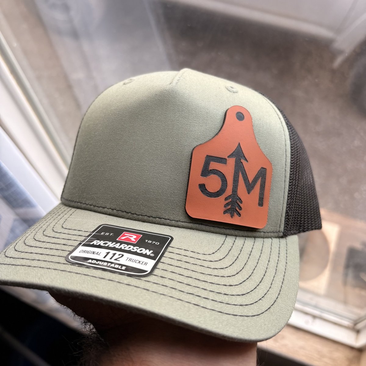 Olive green Richardson trucker hat with a brown leather ear-tag patch by KB Custom Creations