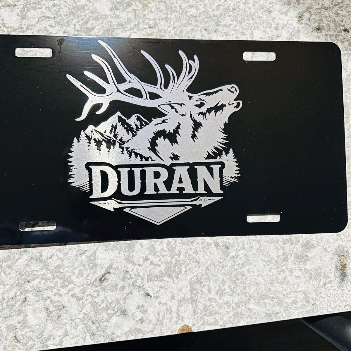 Black engraved license plate with a bugling elk, mountains, and a family name, by KB Custom Creations