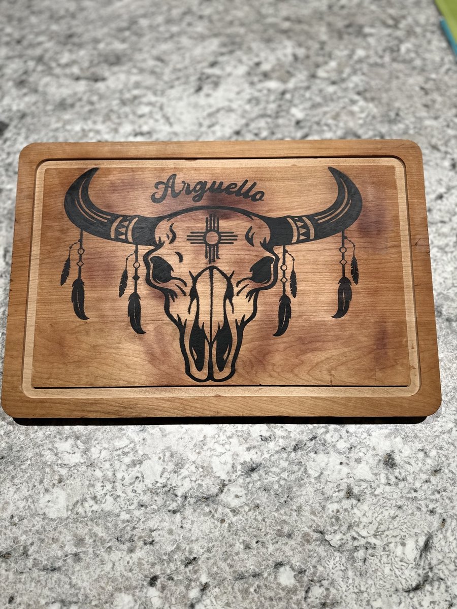 Wood cutting board engraved with a longhorn skull, feathers, a Zia symbol, and a family name, by KB Custom Creations
